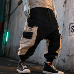 Sarouel homme cargo noir beige en ruelle urbaine, poches visibles, plan 3/4